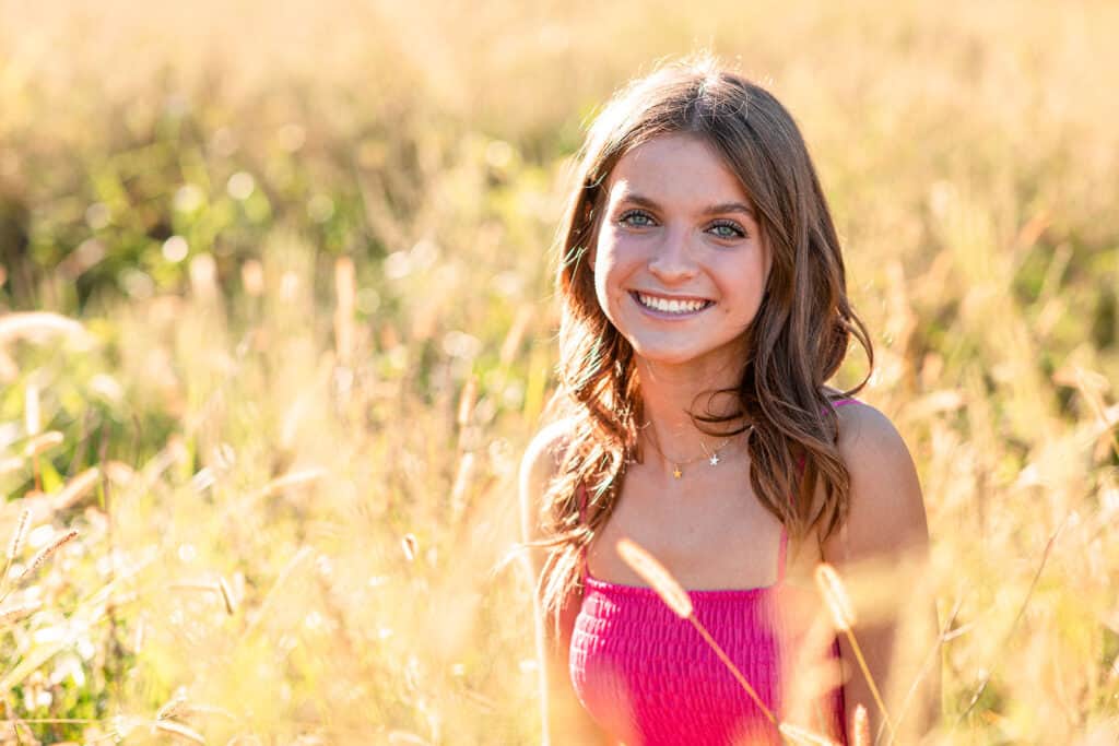 young woman in grassy field with pink dress